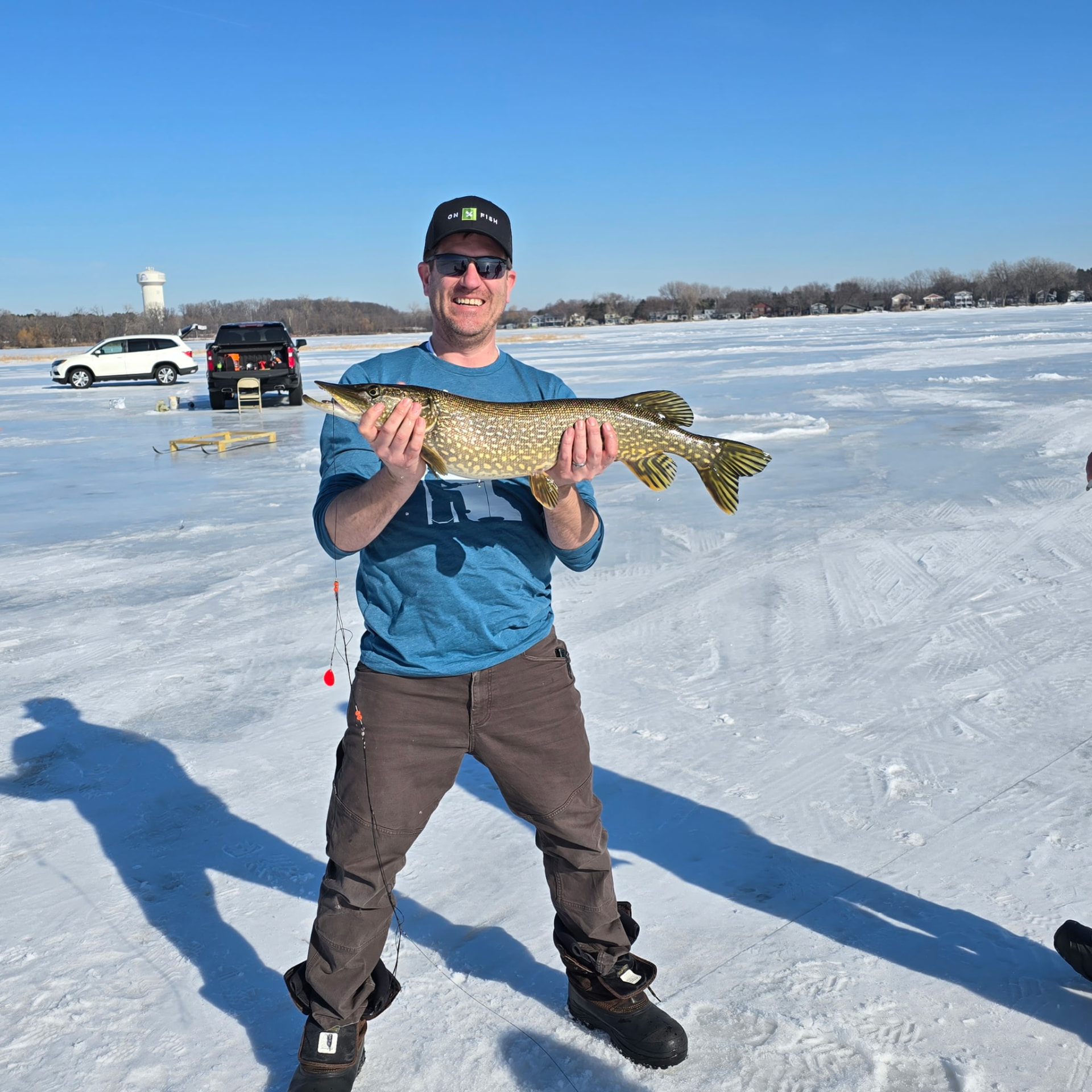 Joe Ackerman ice fishing on a Minnesota lake, holding a northern pike