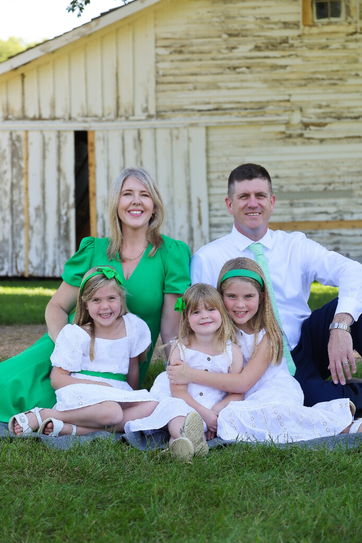 Joe Ackerman with his wife and three daughters in front of a white barn